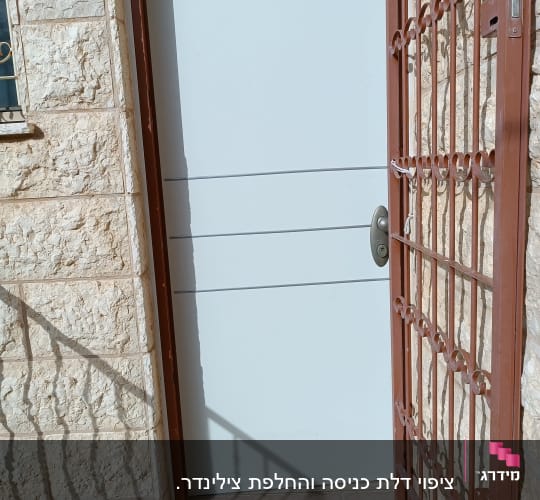 דלת לבנה עם ידית מתכת וסורג חום